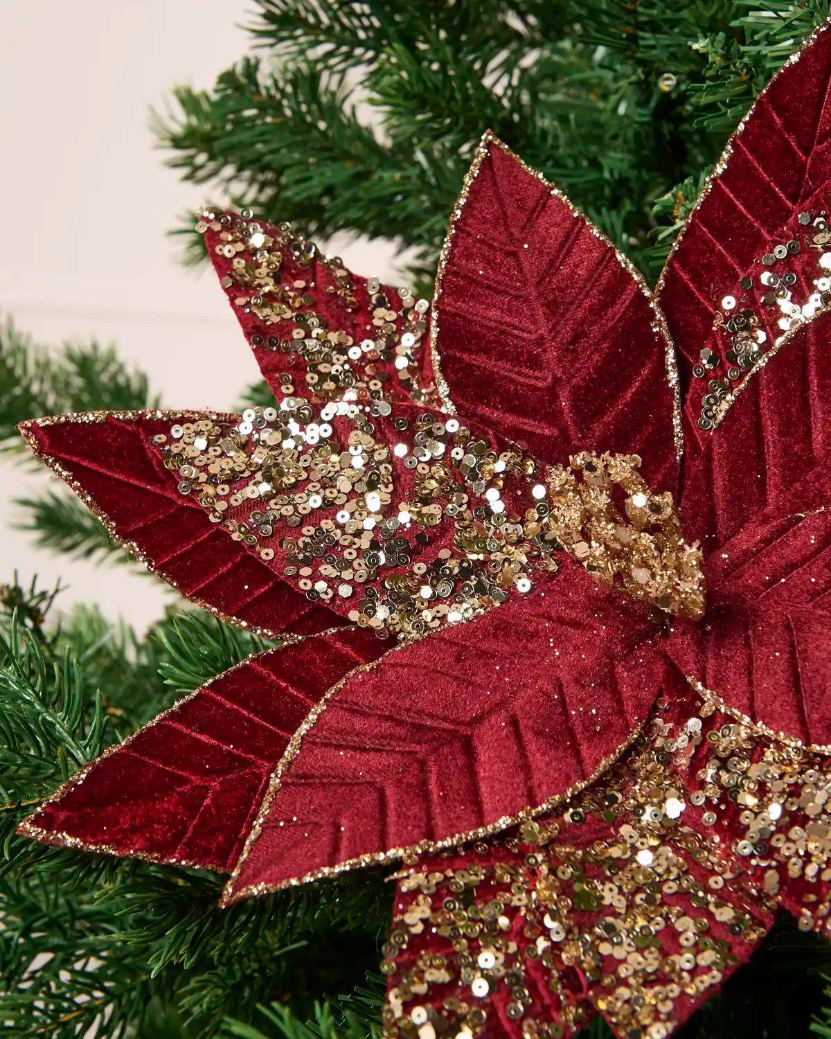 Close-up of a Burgundy & Gold glitter artificial poinsettia flower, highlighting the layered velvet-like petals and gold glitter detailing along the edges and veins
