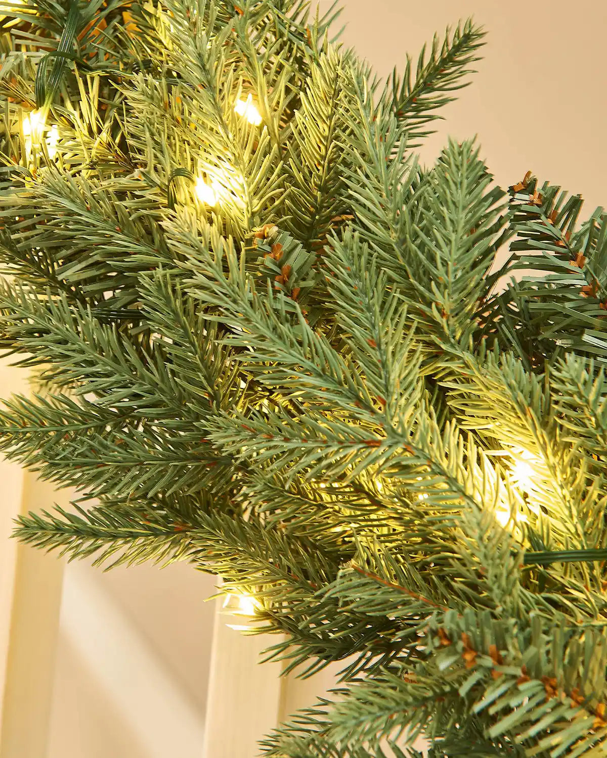 Close-up of a Christmas garland with warm white lights on a beige background