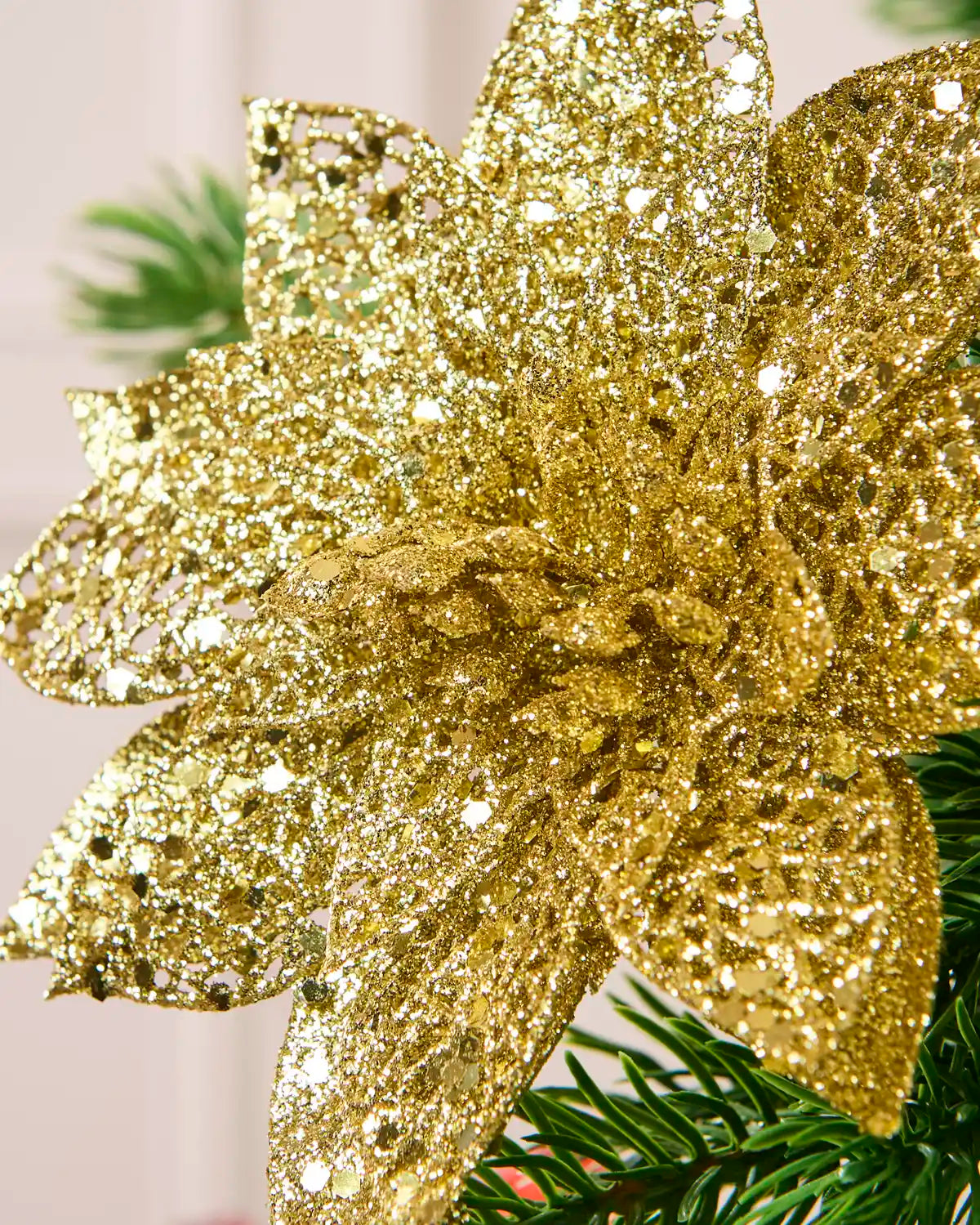 Close-up of a Gold glitter artificial poinsettia flower showing its densely textured, sparkling petals.
