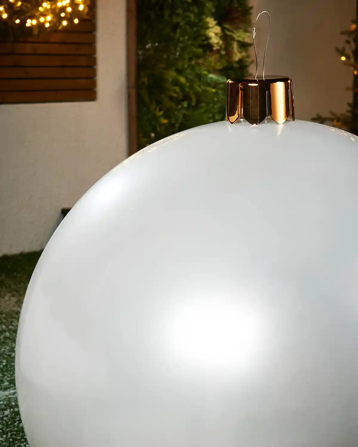 Close-up of a Large white Christmas inflatable bauble with gold cap against a blurred indoor background

