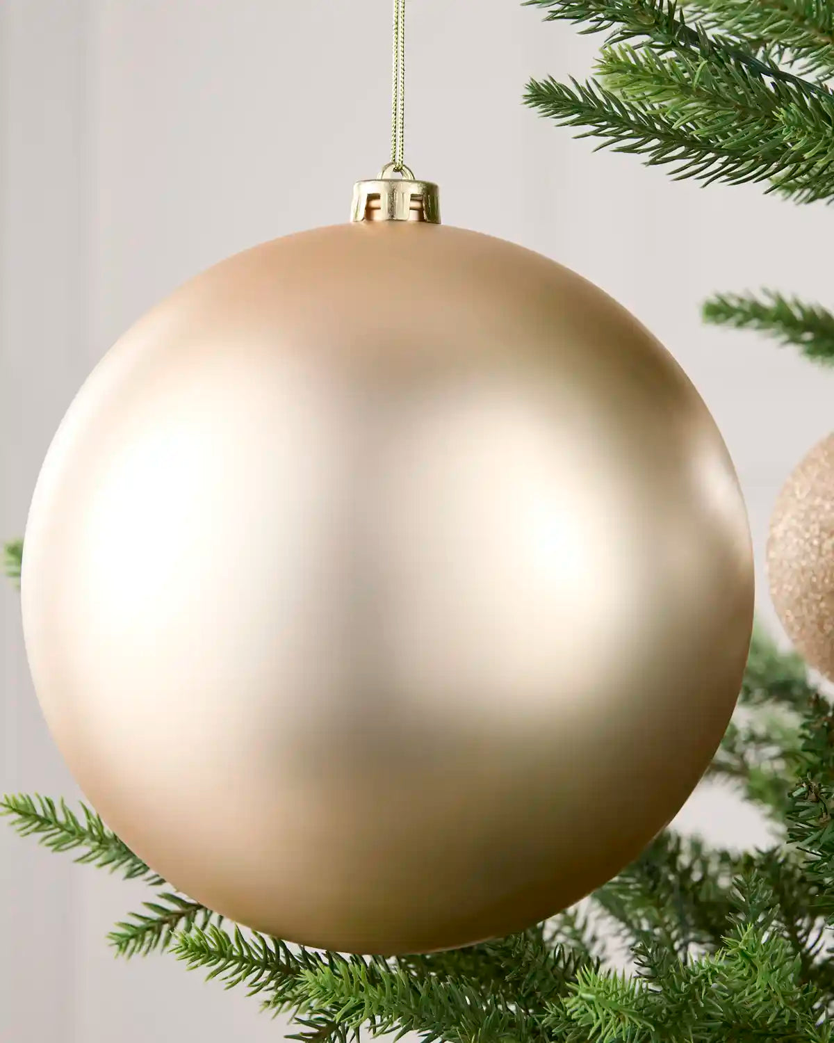 Close-up of a Latte 20 cm oversized shatterproof bauble with a smooth matt finish on a Christmas tree.

