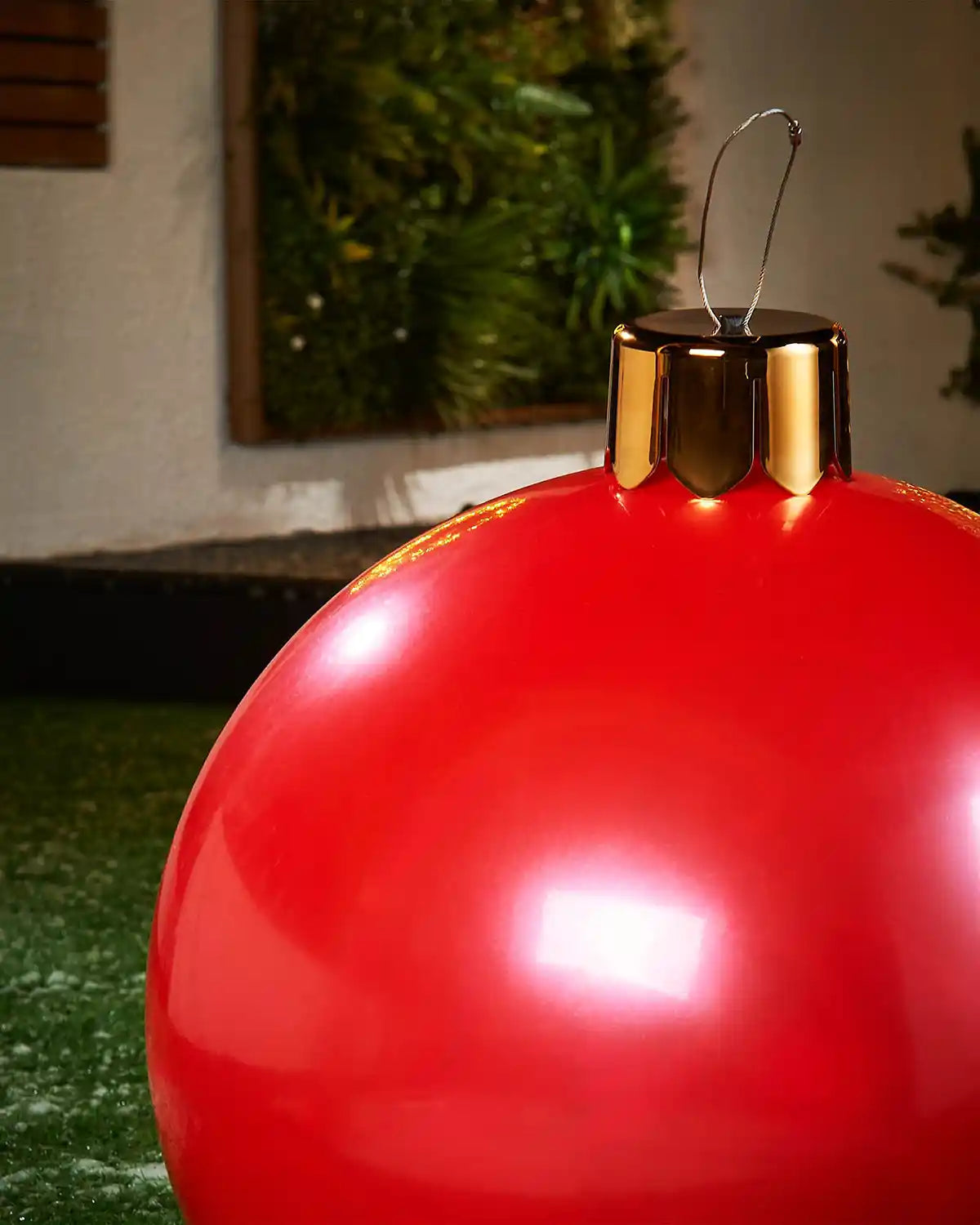 Close-up of a Medium red Christmas inflatable bauble with gold cap against a blurred indoor background