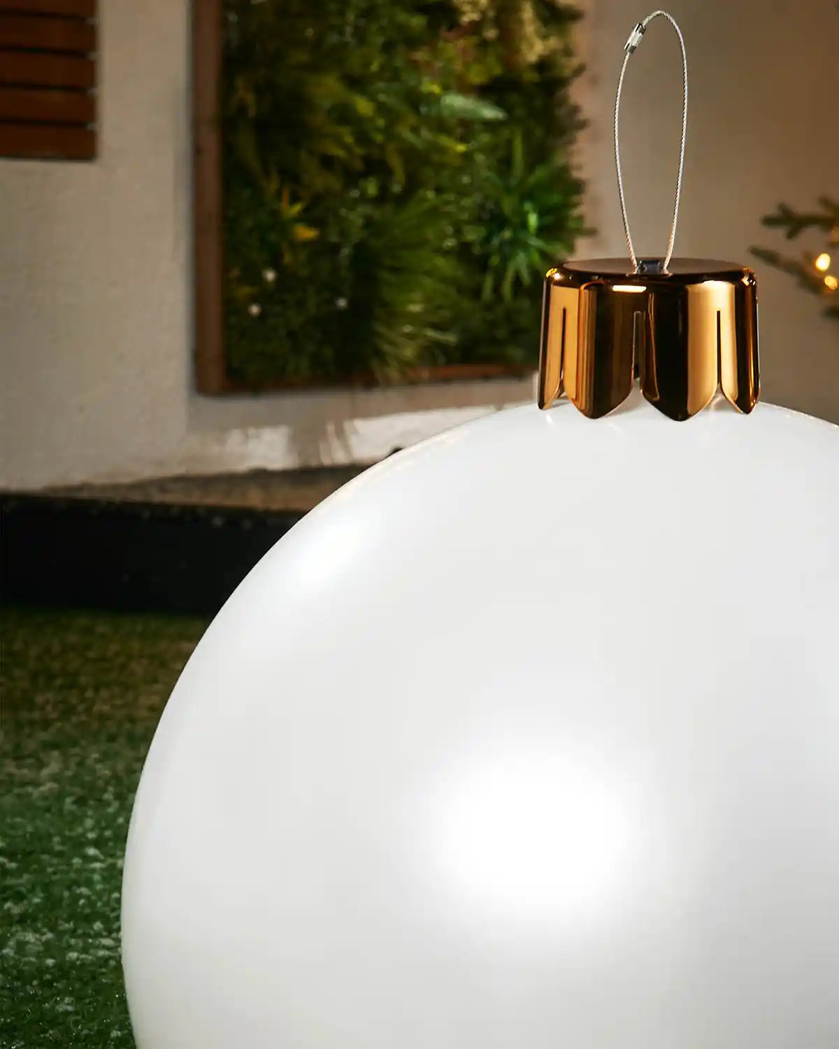 Close-up of a Medium white Christmas inflatable bauble with gold cap against a blurred indoor background
