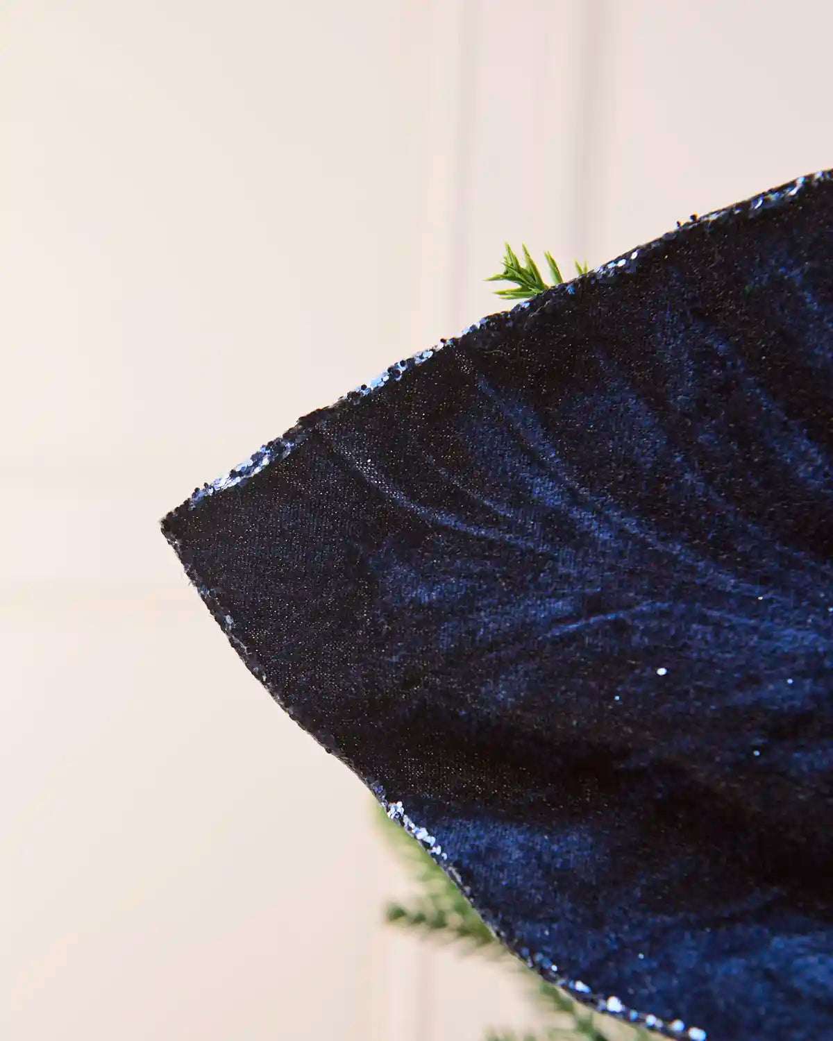 Close-up of a Navy velvet poinsettia petal, showcasing its soft texture, detailed veining and shimmering glittered edge