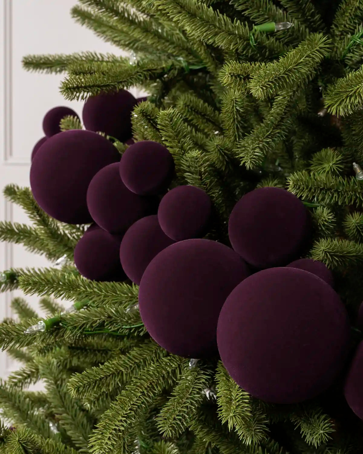 Close-up of a Purple Velvet Bauble Garland on a Christmas tree, featuring soft purple velvet baubles.