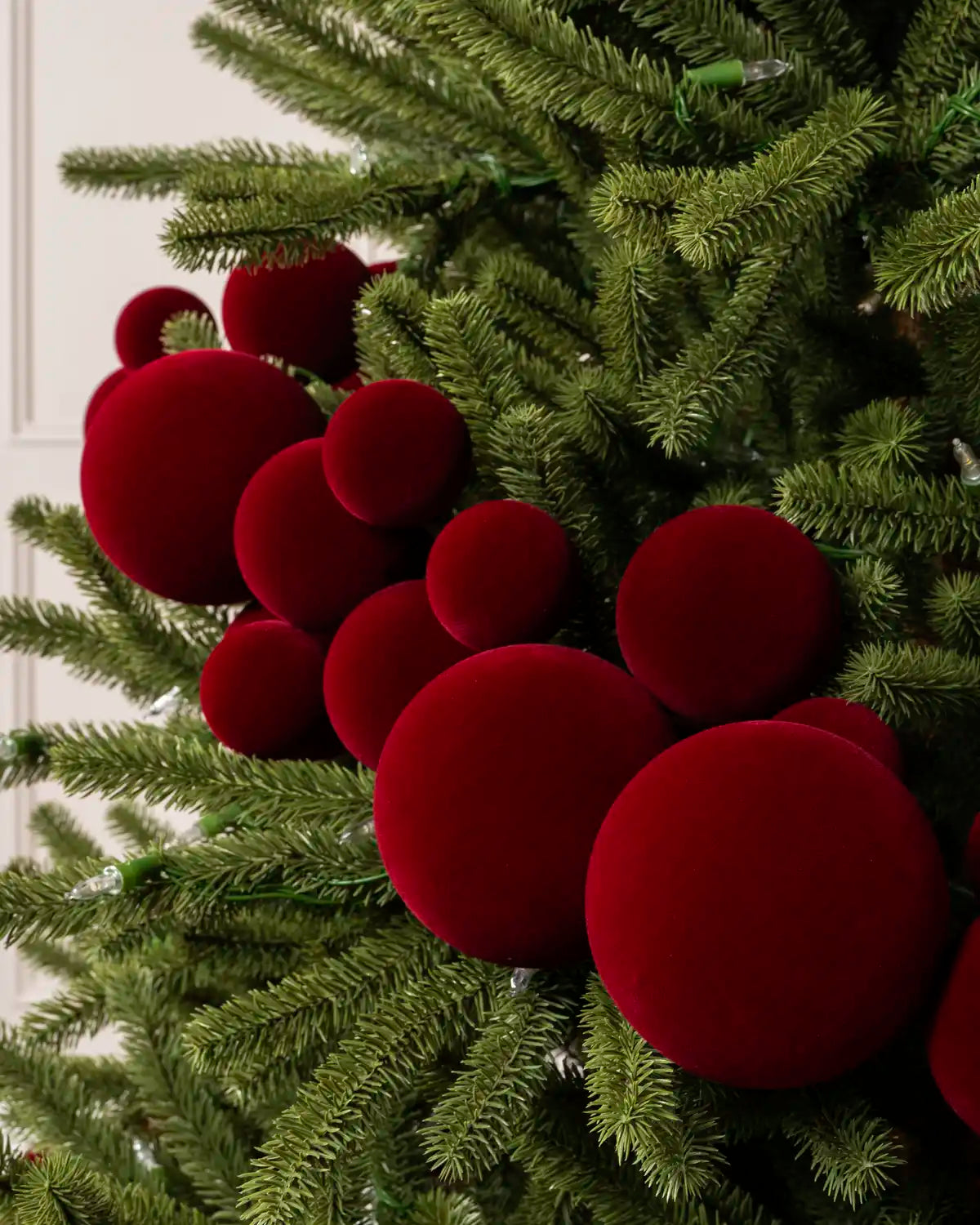 Close-up of a Red Velvet Bauble garland on a Christmas tree, featuring soft red velvet baubles
