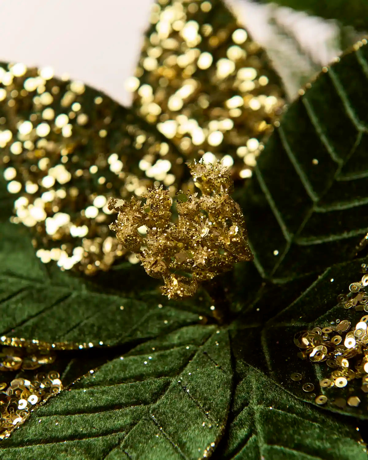 Close-up of a Sage Green & Gold glitter artificial poinsettia flower, highlighting the layered velvet-like petals and gold glitter detailing along the edges and veins
