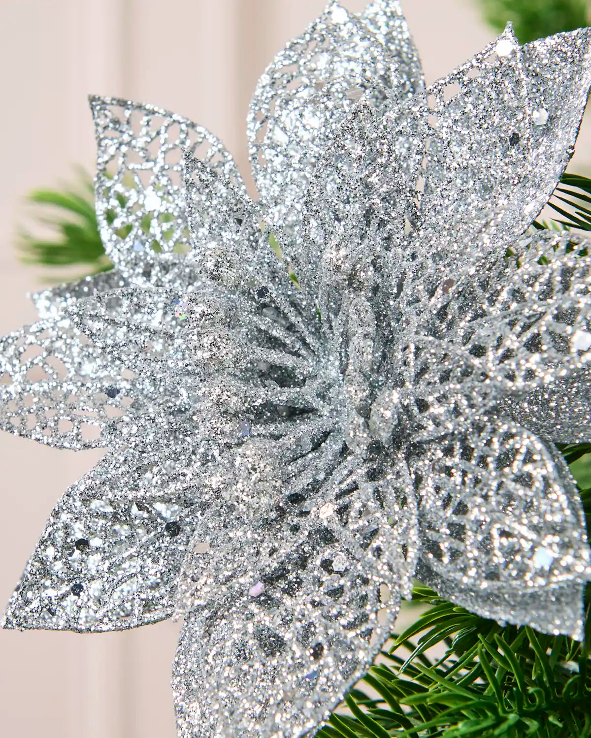 Close-up of a Silver glitter artificial poinsettia flower showing its densely textured, sparkling petals.
