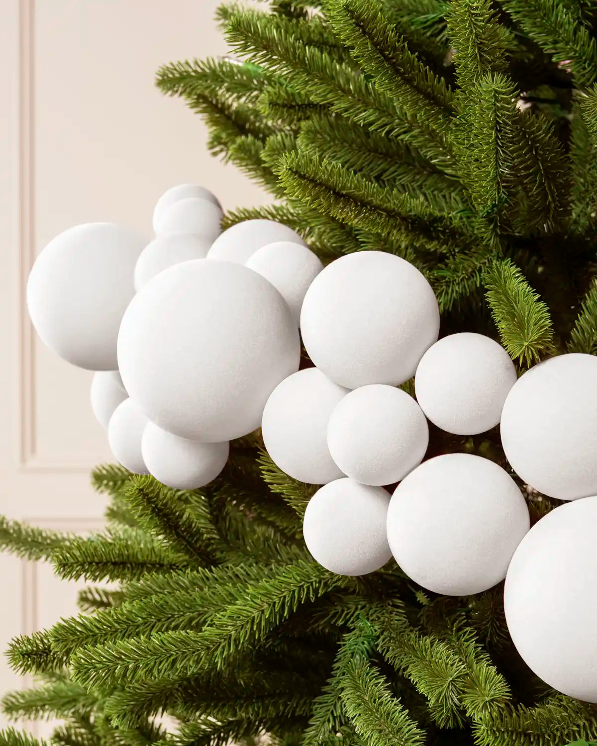 Close-up of a White Velvet Bauble Garland on a Christmas tree, featuring soft white velvet baubles.