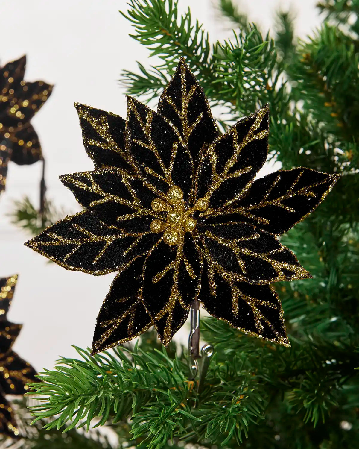 Close-up of a black glitter artificial poinsettia with gold glitter leaf detailing