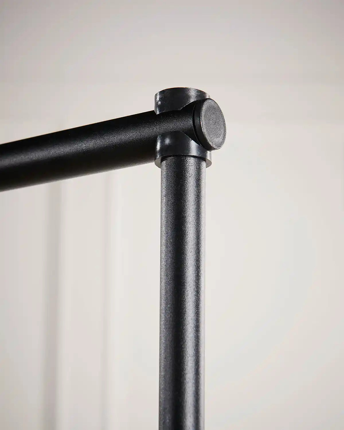 Close-up of a black metal rod with a cylindrical fitting on a light gray background