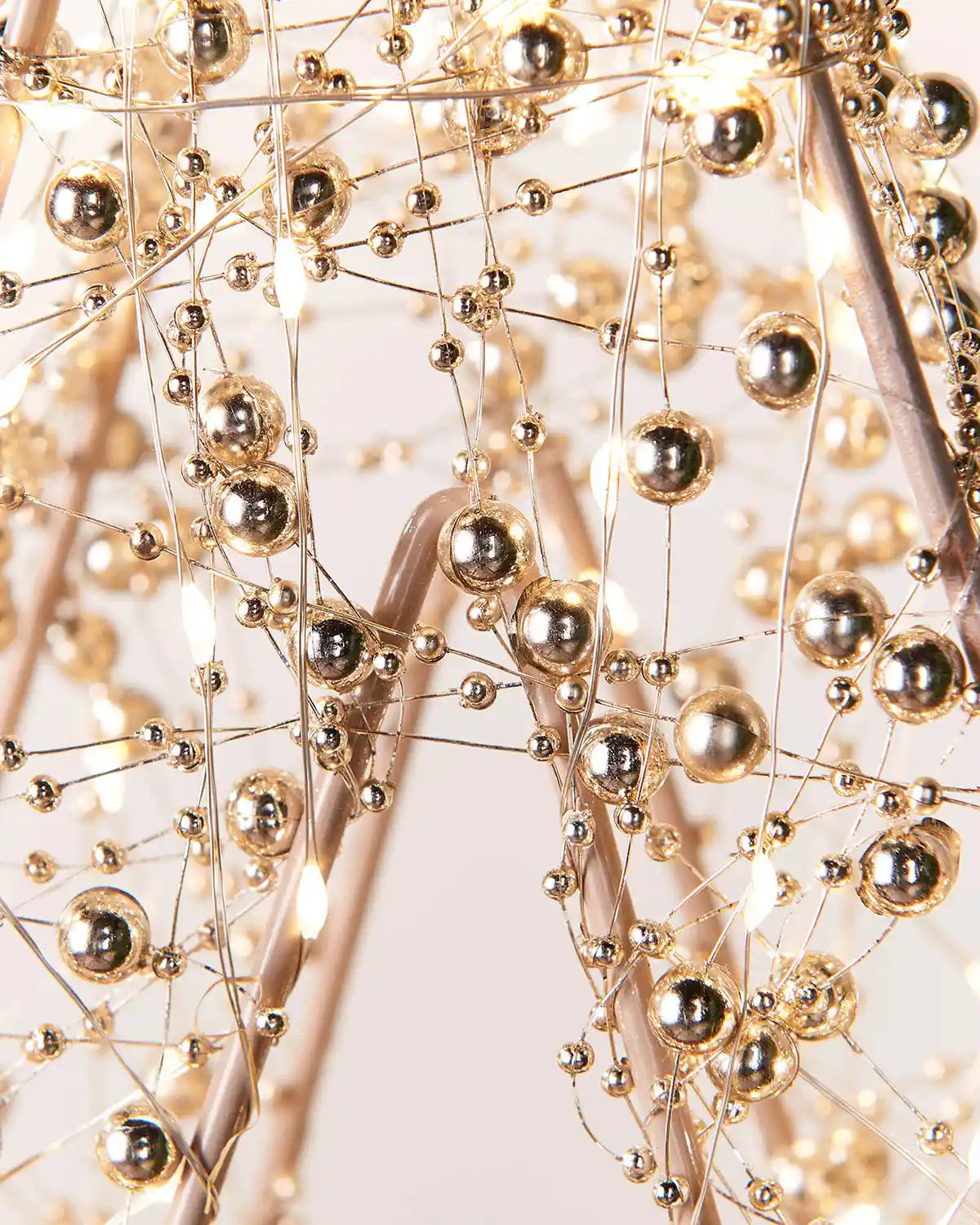 Close-up of a decorative light fixture with gold spherical beads on a white background