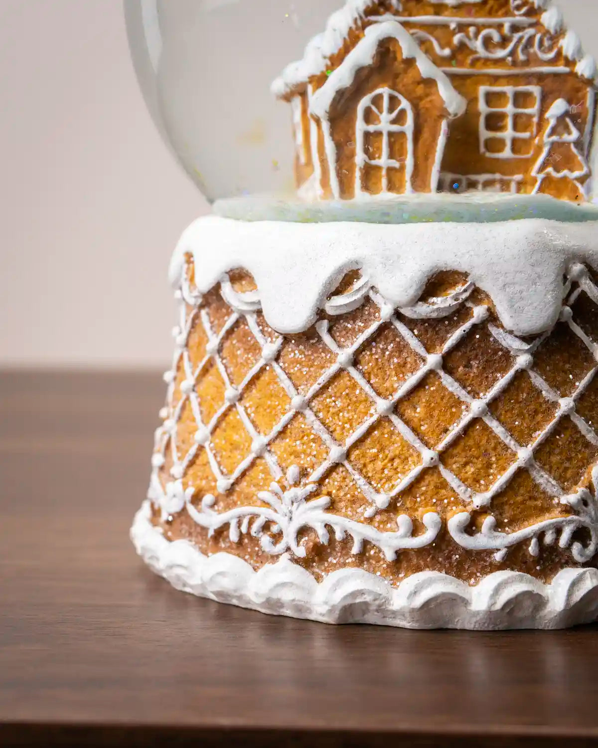 Close-up of a gingerbread snow globe showing the base with white icing lattice patterns and the lower