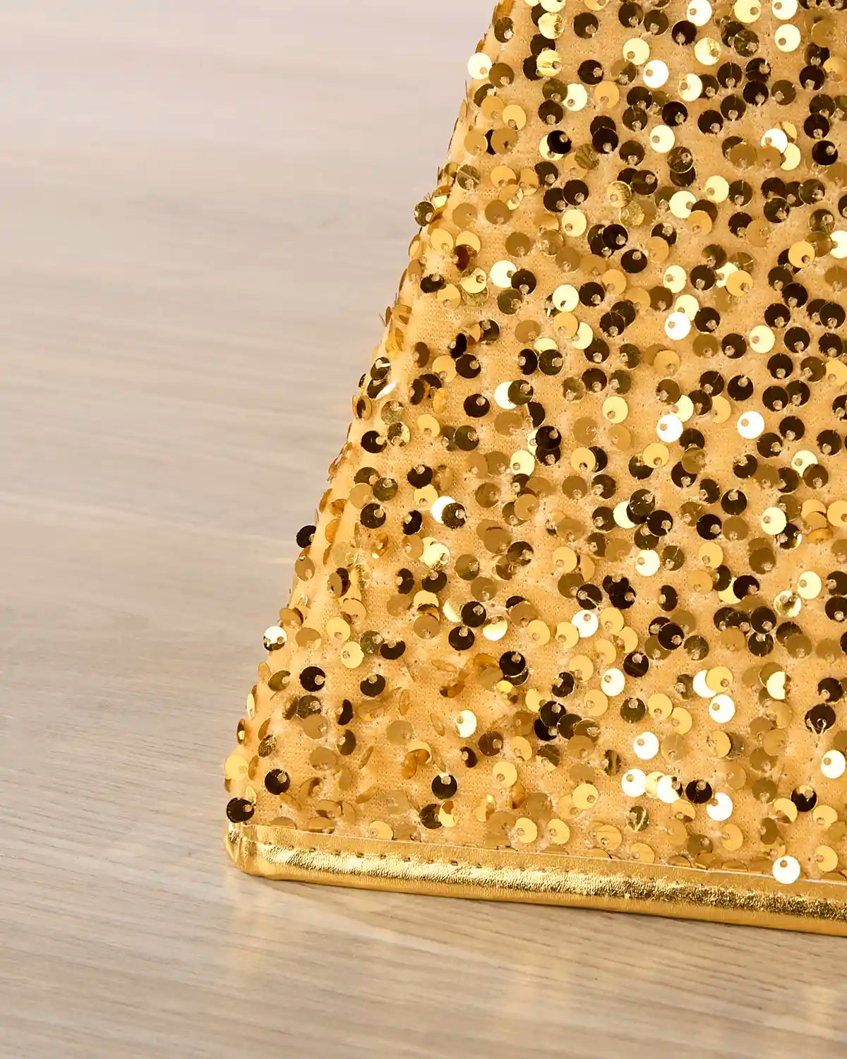 Close-up of a gold sequined Christmas tree collar on a wooden floor