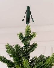 Close-up of a green Christmas tree topper holder secured to the top branch of an artificial Christmas tree
