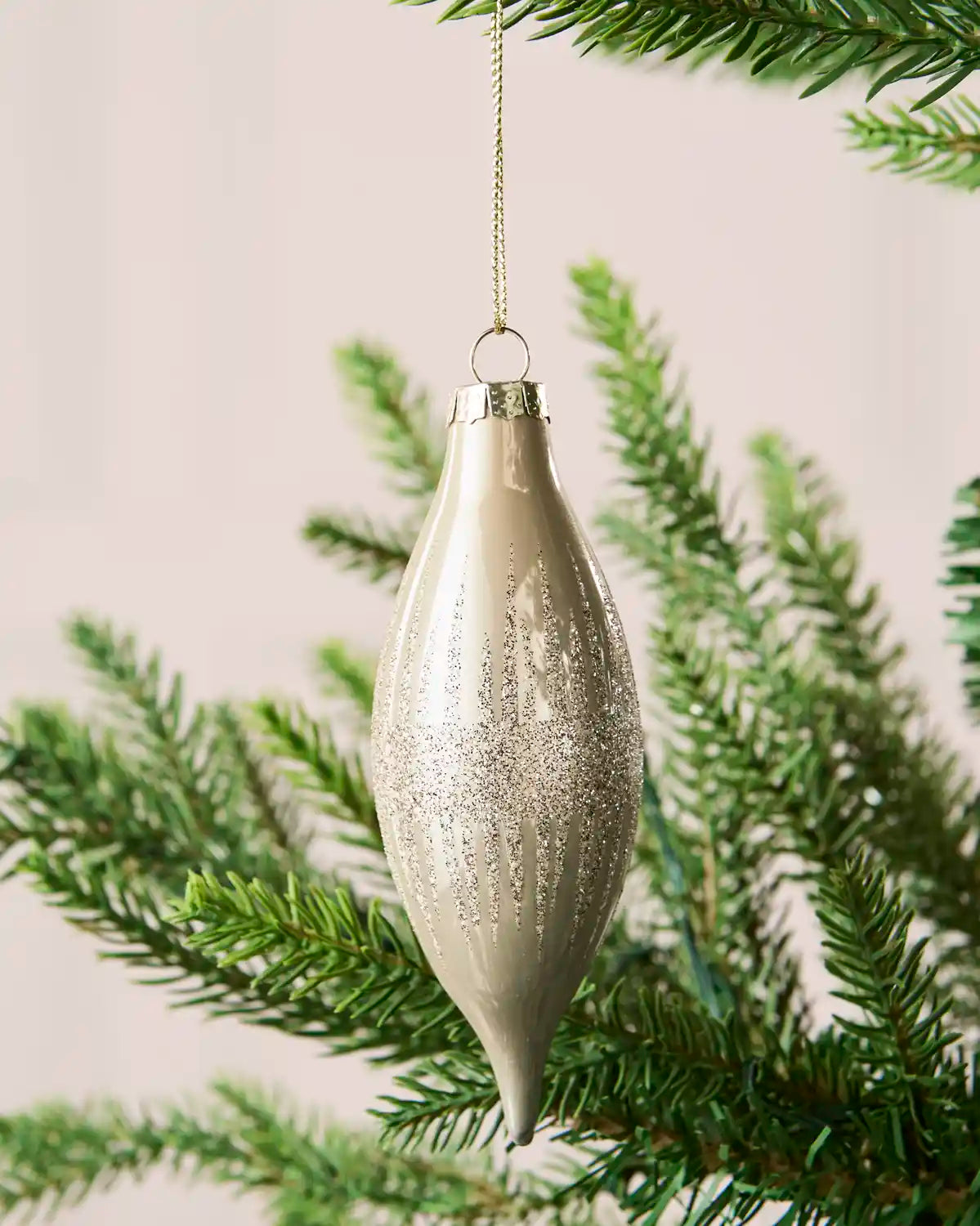 Close-up of a latte teardrop glass bauble with glitter lines and a central glitter band.
