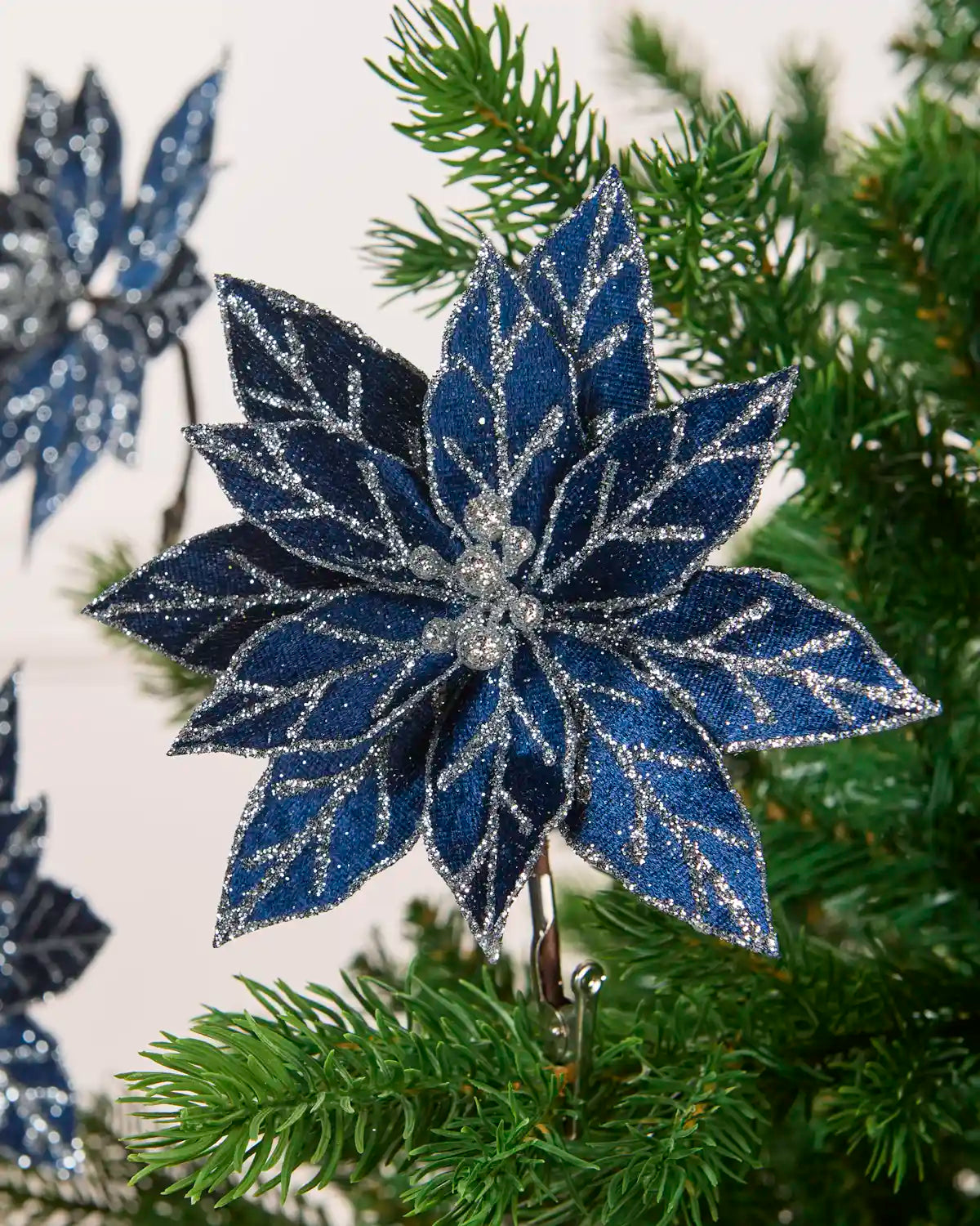 Close-up of a navy blue glitter artificial poinsettia with silver sequined detailing