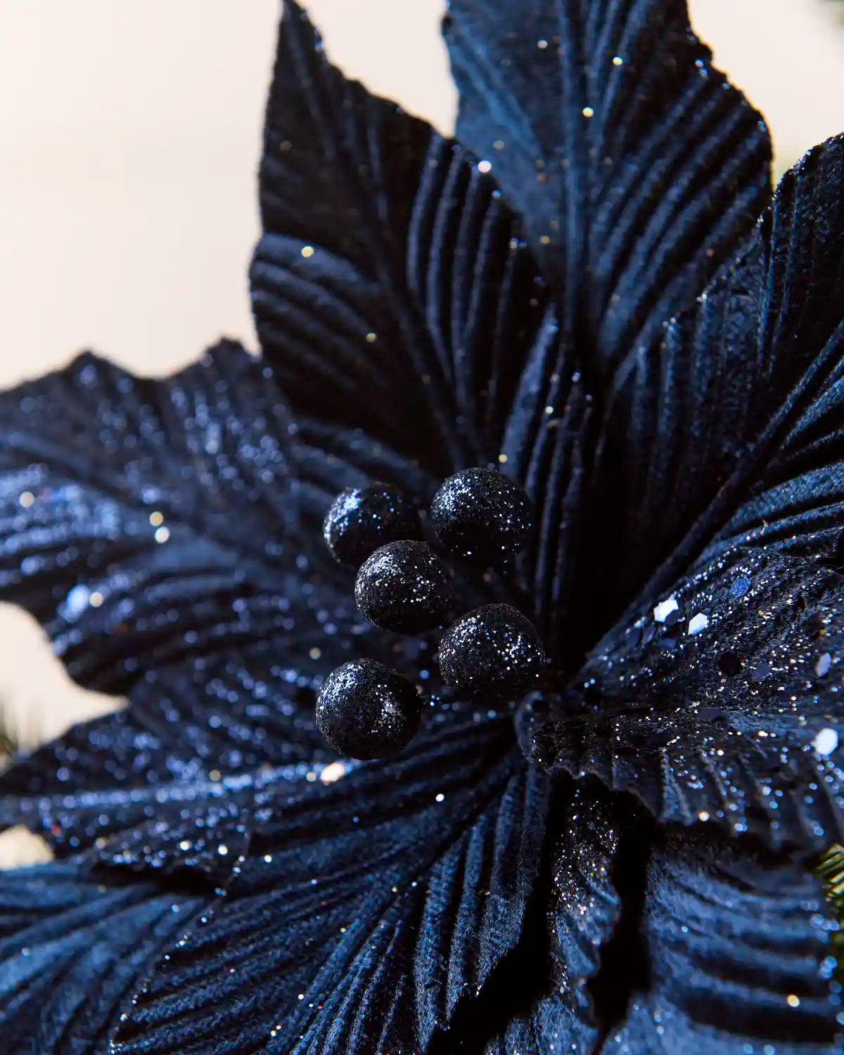 Close-up of a navy blue glitter artificial poinsettia with navy glitter berries at the centre
