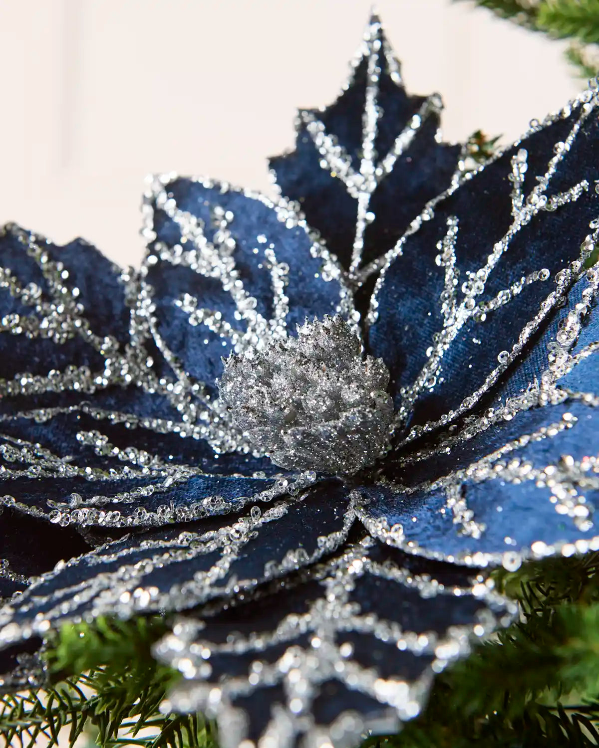 Close-up of a navy blue glitter artificial poinsettia with silver glitter detailing