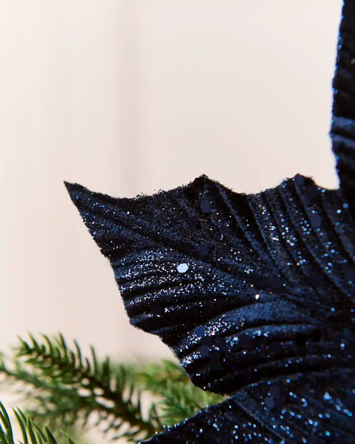 Close-up of a navy blue glitter poinsettia petal showing its textured finish and glitter