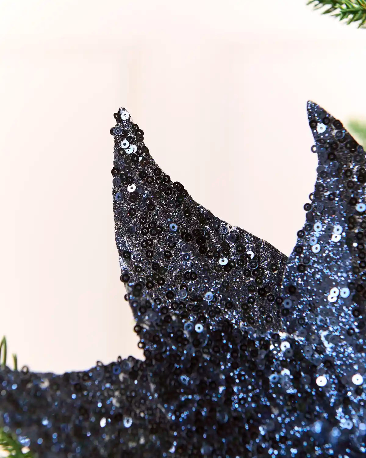 Close-up of a navy sequined poinsettia  flower, with blue sequins against a soft light background.