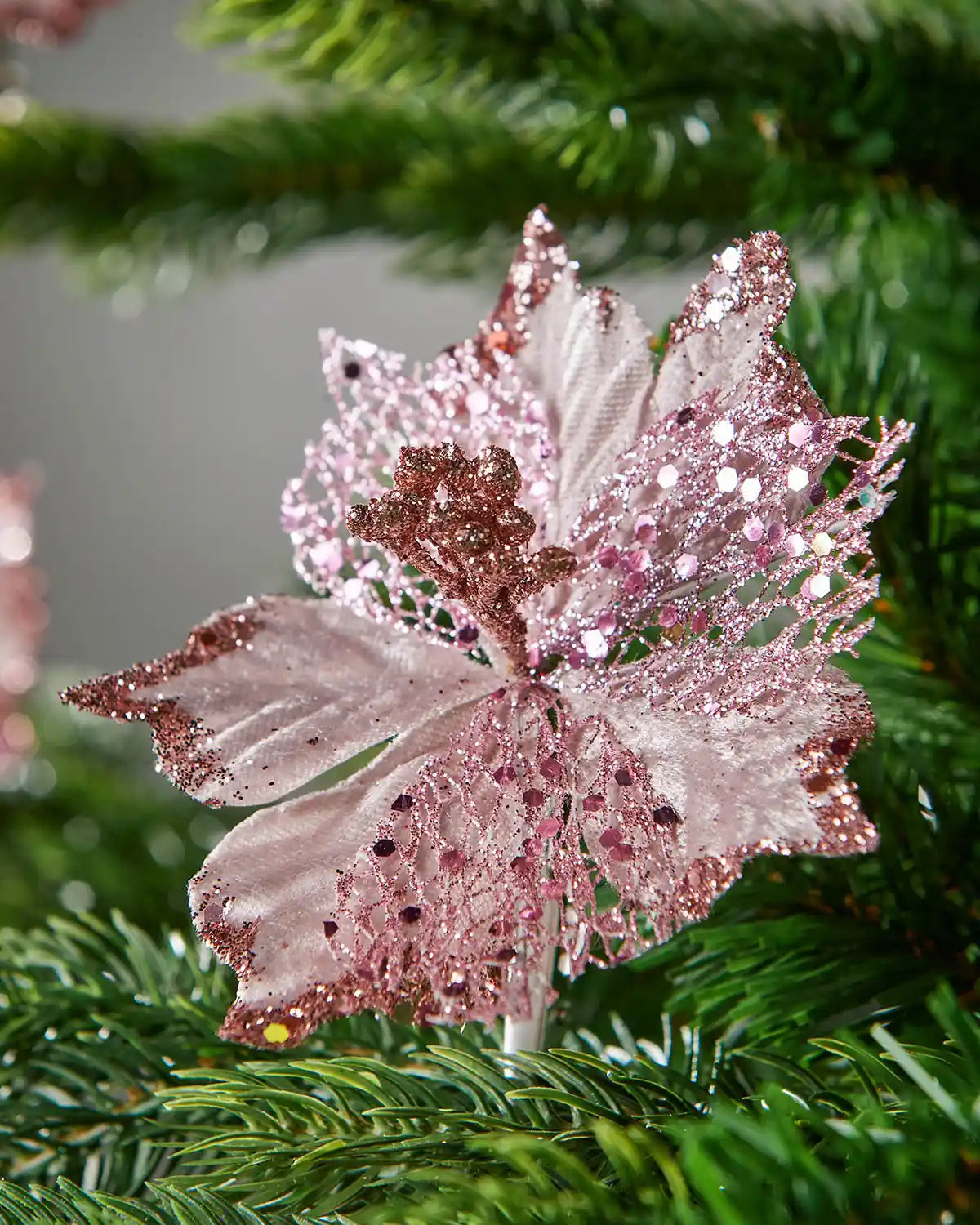 Close-up of a pink and white decorative leaf with glitter texture against a blurred green background