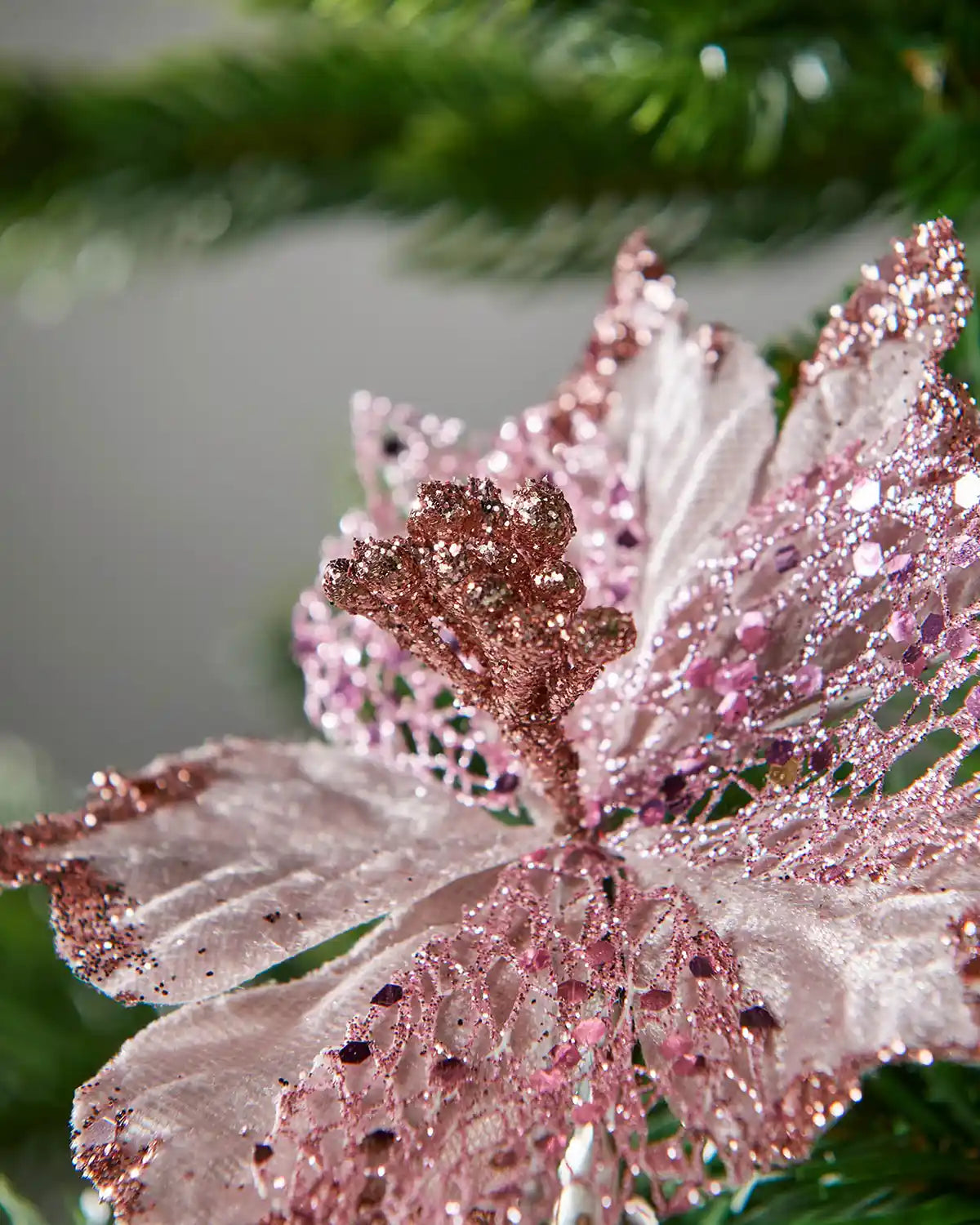 Close-up of a pink and white decorative leaf with glittery texture against a blurred green background