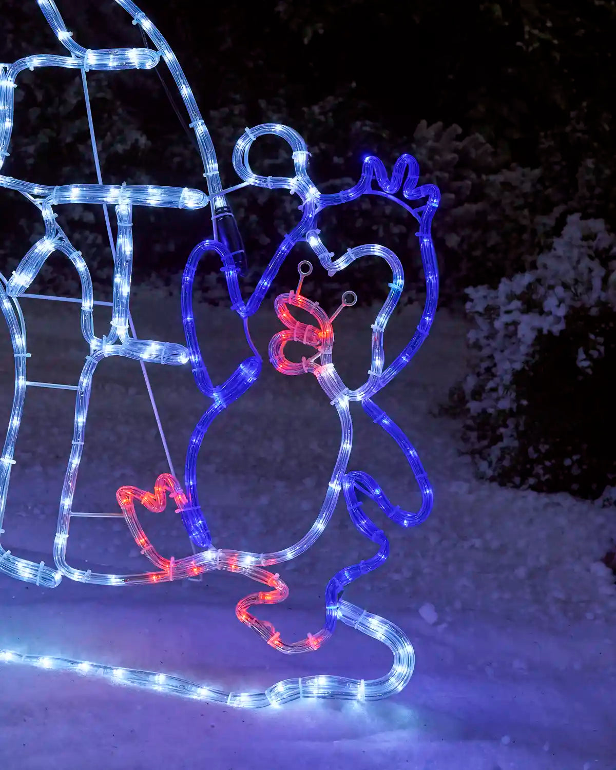 Close-up of a pre-lit penguin rope light silhouette beside an igloo, with blue and white lights outlining the penguin and red accents on its beak and feet