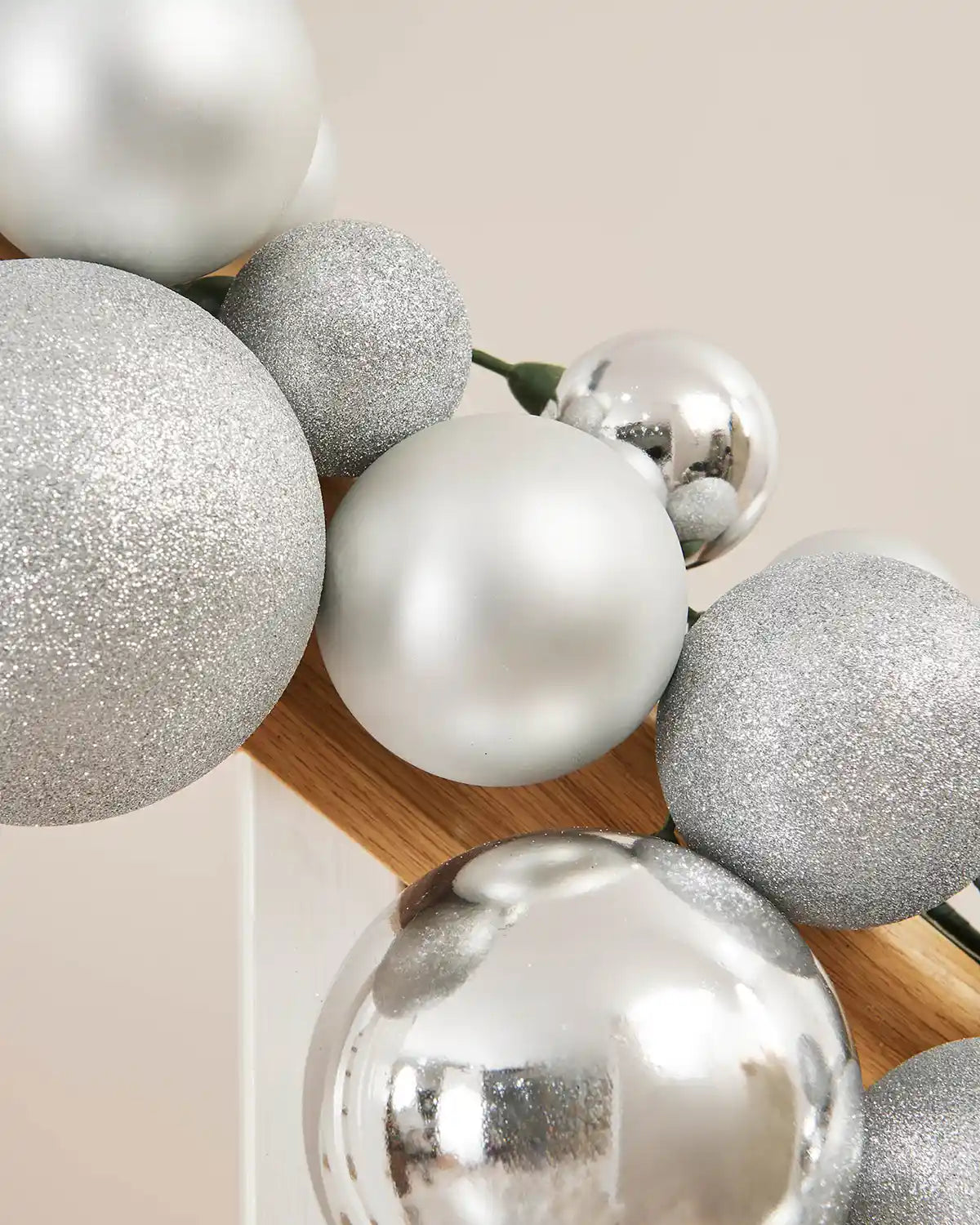 Close-up of a silver bauble garland on a staircase banister against a cream wall
