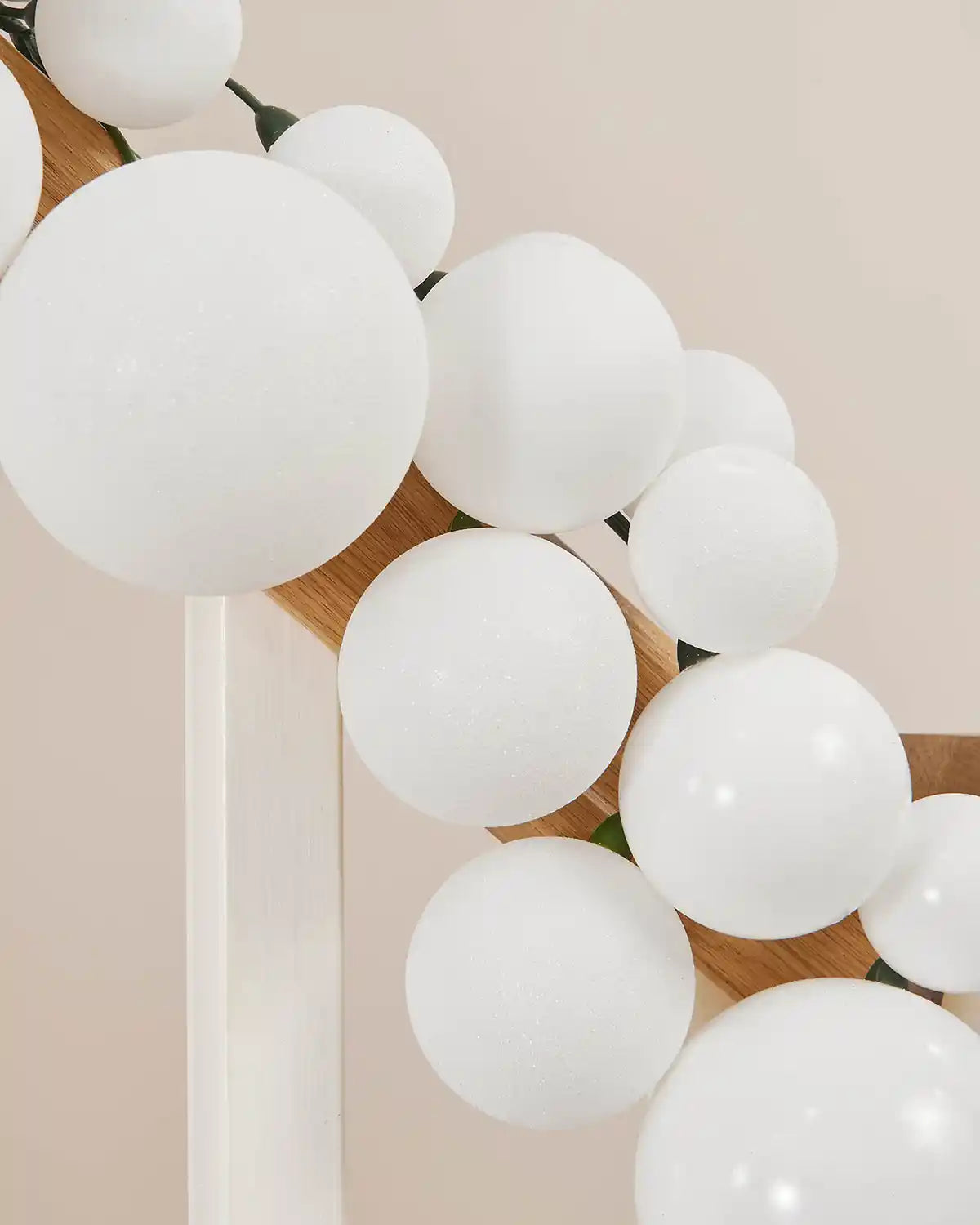 Close-up of a white bauble garland on a staircase banister against a cream wall
