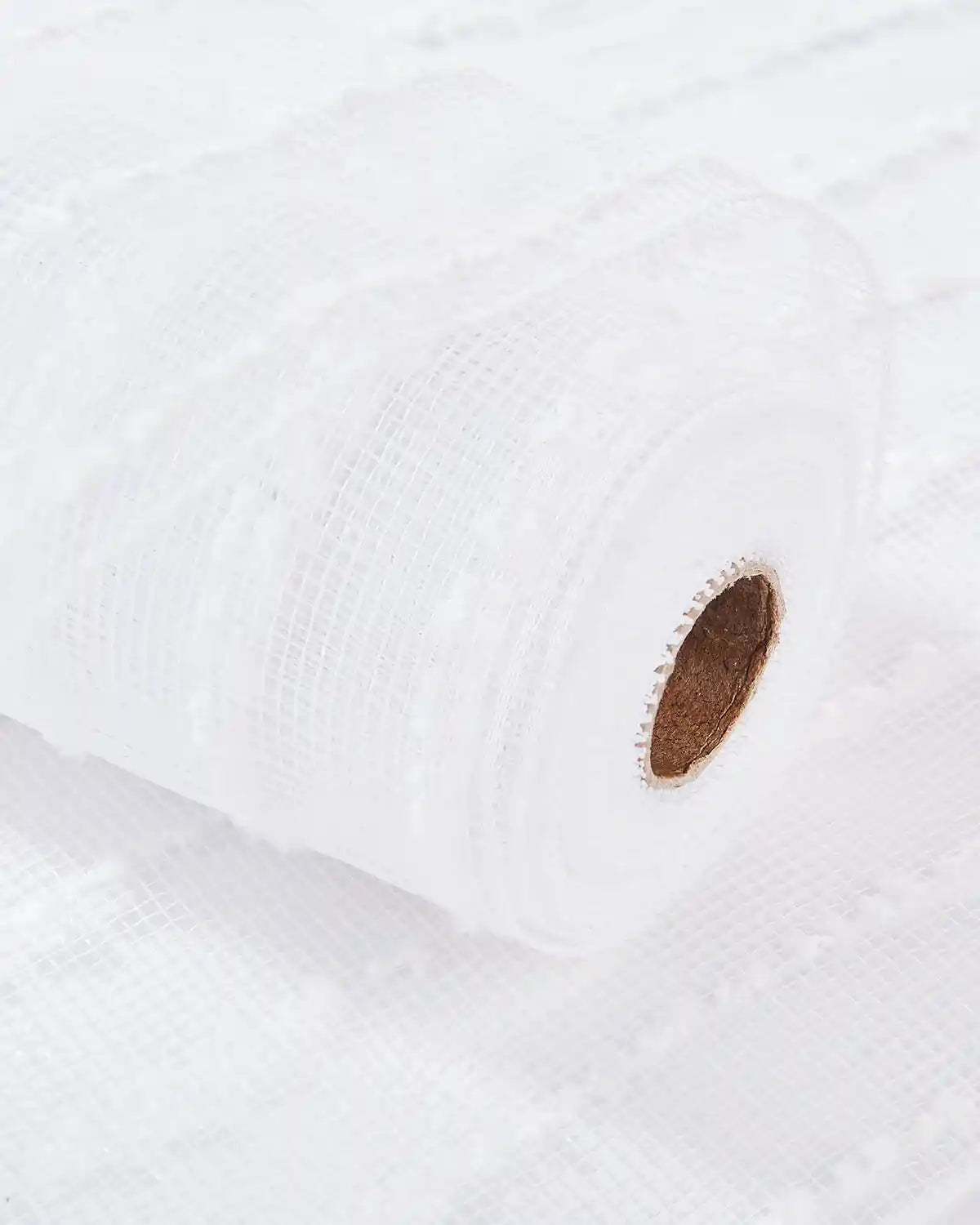 Close-up of a white lace pattern mesh ribbon on a white table 