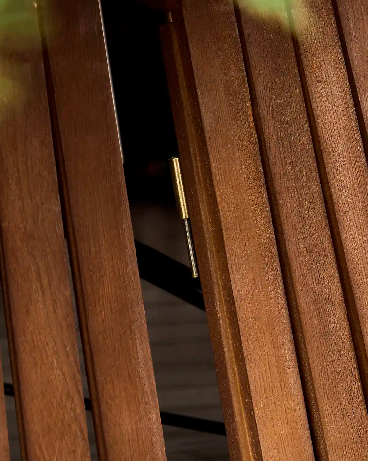 Close-up of a wooden slatted screen or door with a brass-colored metal latch mechanism visible between the vertical wood panels.