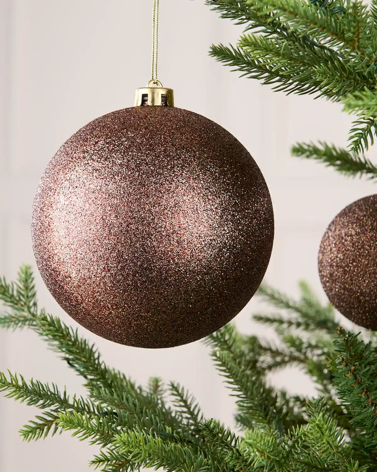 Close-up of an Espresso 15 cm oversized shatterproof bauble with a Glitter finish on a Christmas tree.
