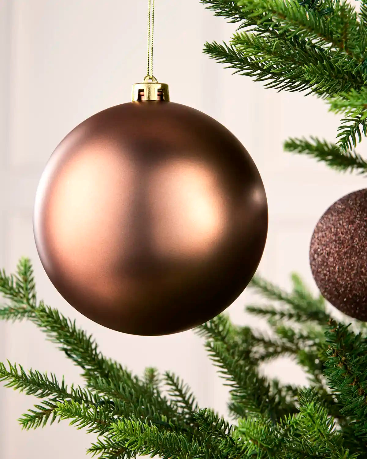 Close-up of an Espresso 15 cm oversized shatterproof bauble with a Matt finish on a Christmas tree.
