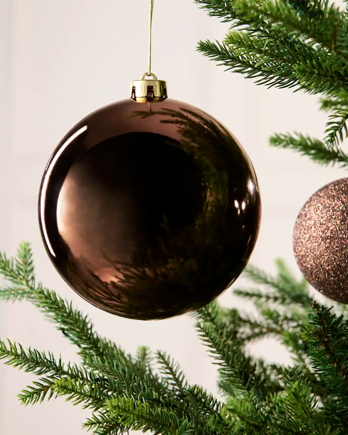 Close-up of an Espresso 15 cm oversized shatterproof bauble with a Shiny finish on a Christmas tree.
