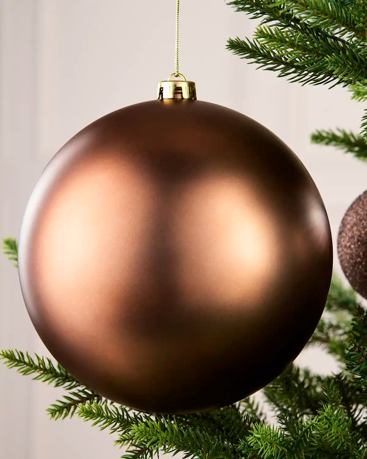 Close-up of an Espresso 20 cm oversized shatterproof bauble with a Matt finish on a Christmas tree.

