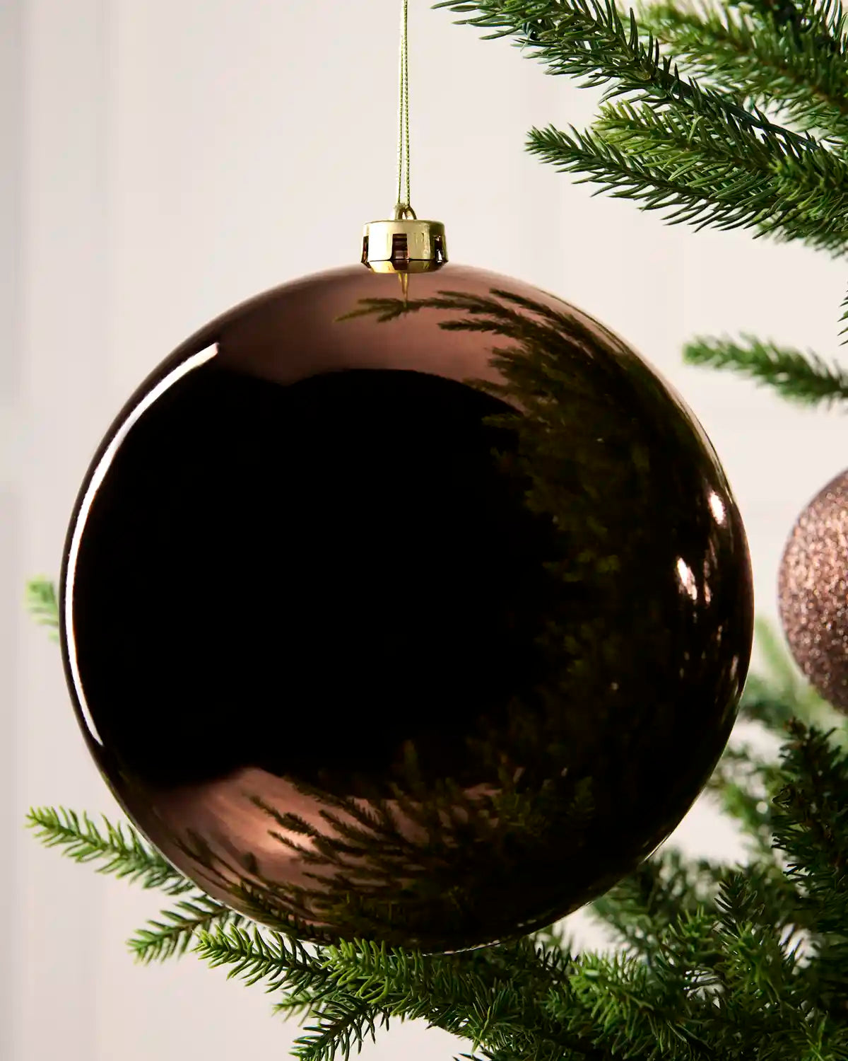 Close-up of an Espresso 20 cm oversized shatterproof bauble with a Shiny finish on a Christmas tree.
