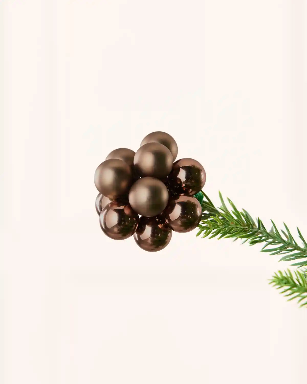 Close-up of an Espresso glass berry cluster bauble attached to a Christmas tree branch.
