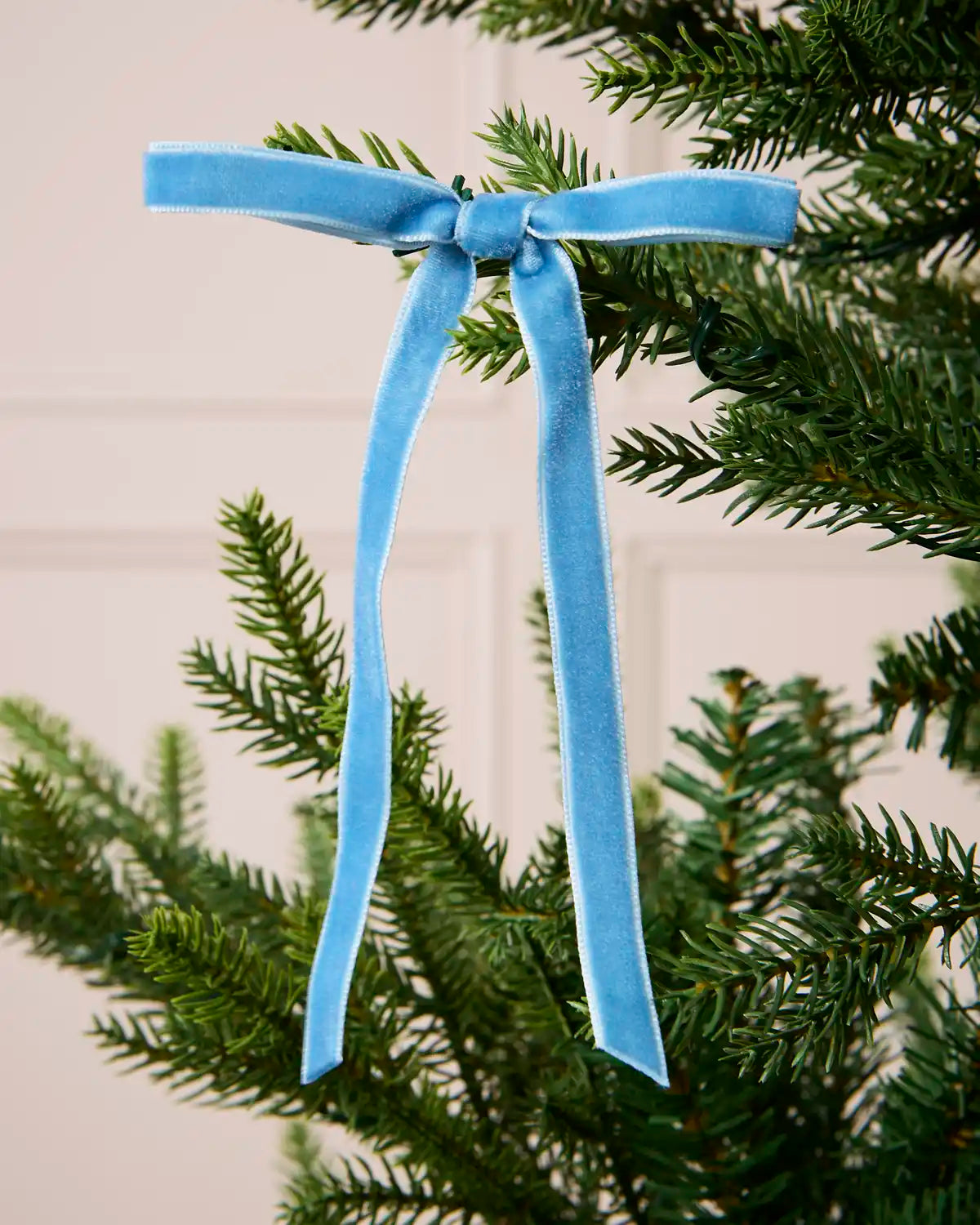 Close-up of an Ice Blue Velvet Bow attached to a Christmas tree branch