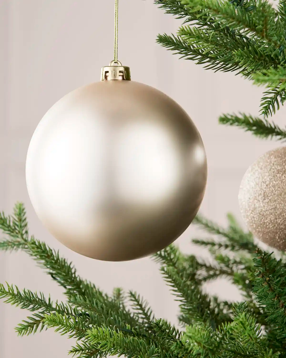 Close-up of an Latte 15 cm oversized shatterproof bauble with a smooth matt finish on a Christmas tree.
