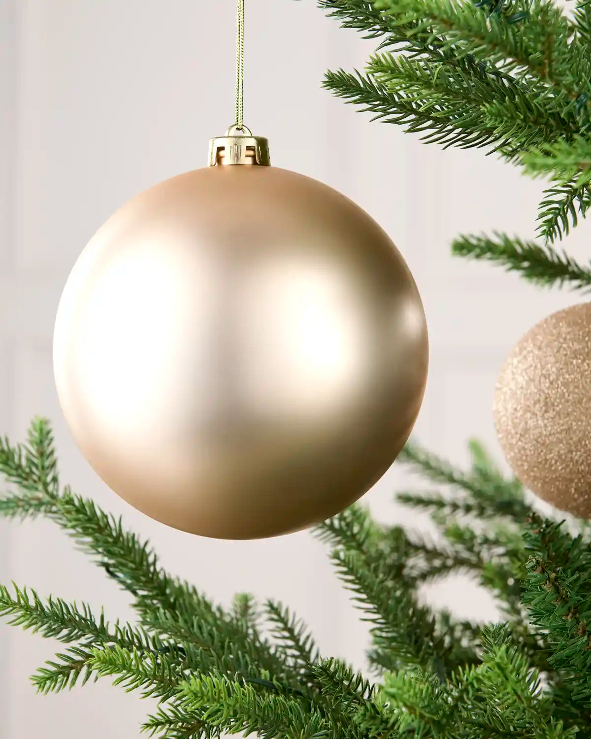 Close-up of an Latte 15 cm oversized shatterproof bauble with a smooth matt finish on a Christmas tree.
