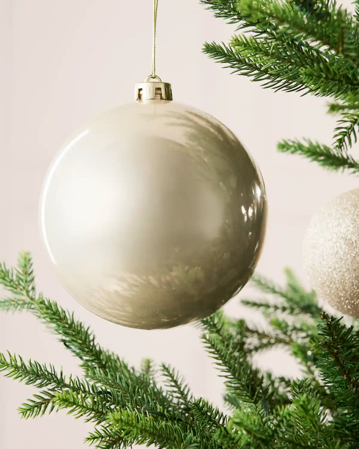 Close-up of an Latte 15 cm oversized shatterproof bauble with a smooth shiny finish on a Christmas tree.
