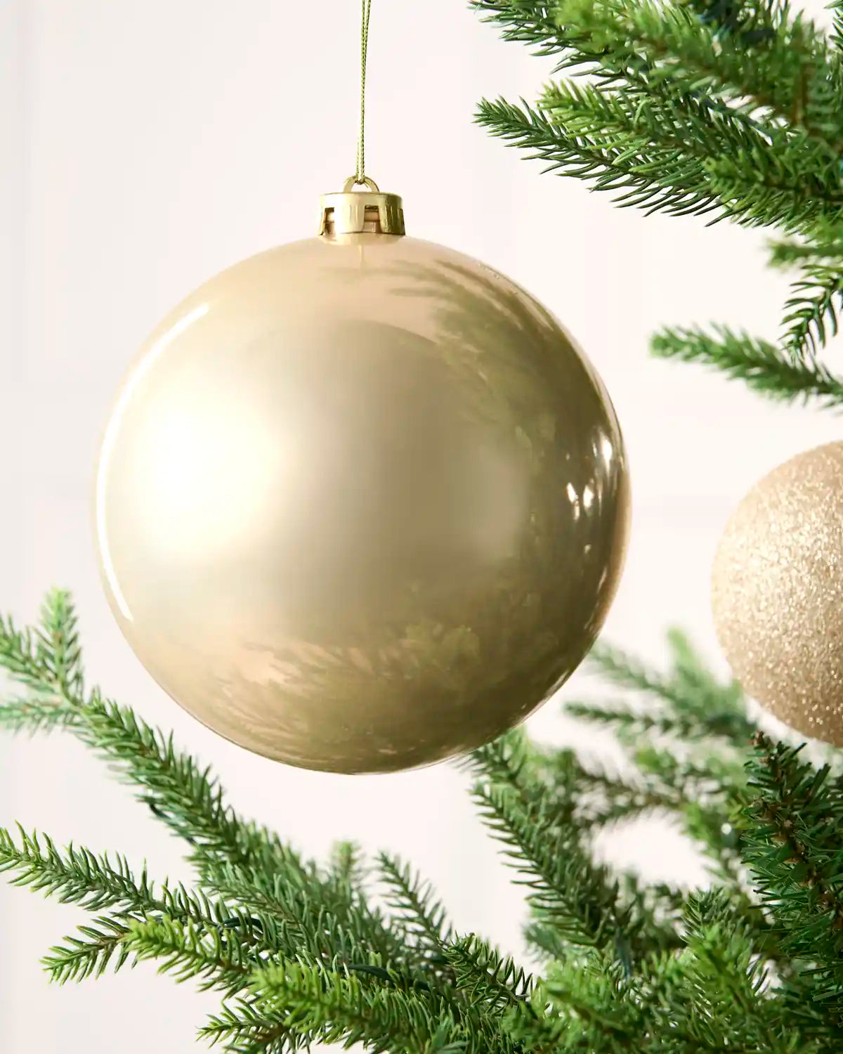 Close-up of an Latte 15 cm oversized shatterproof bauble with a smooth shiny finish on a Christmas tree.
