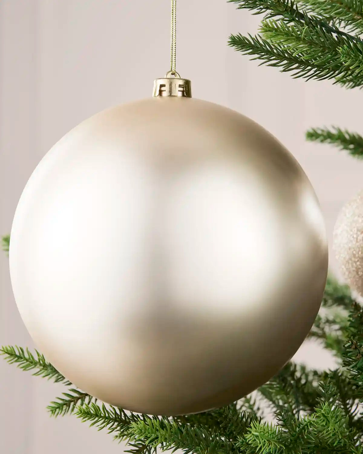 Close-up of an Latte 20 cm oversized shatterproof bauble with a smooth matt finish on a Christmas tree.
