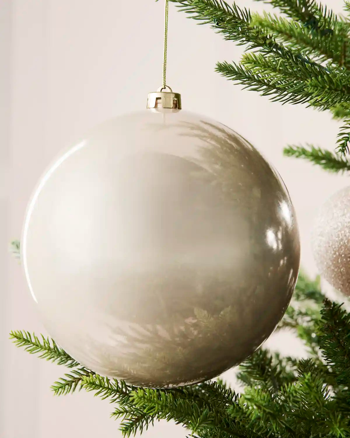 Close-up of an Latte 20 cm oversized shatterproof bauble with a smooth shiny finish on a Christmas tree.
