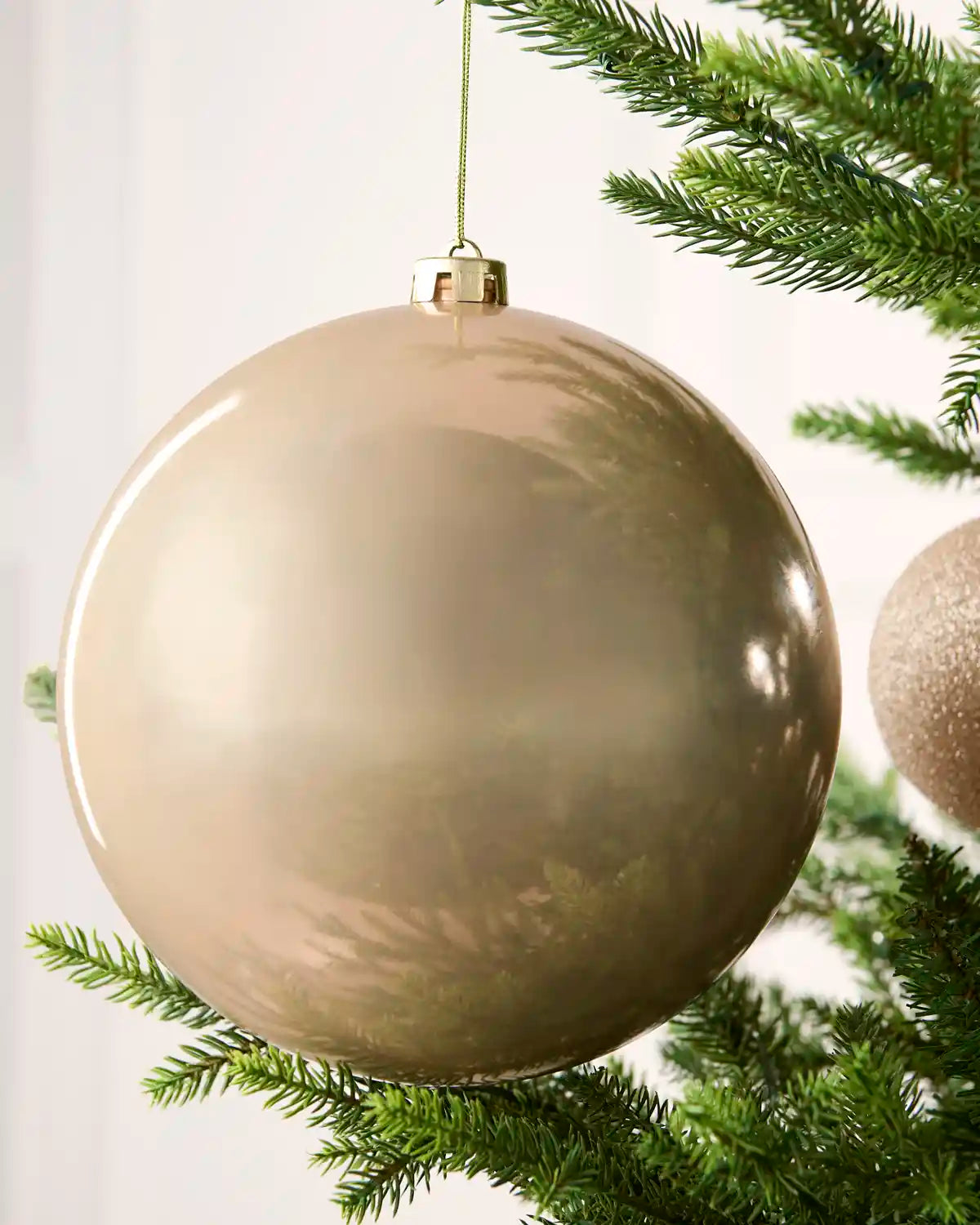 Close-up of an Latte 20 cm oversized shatterproof bauble with a smooth shiny finish on a Christmas tree.
