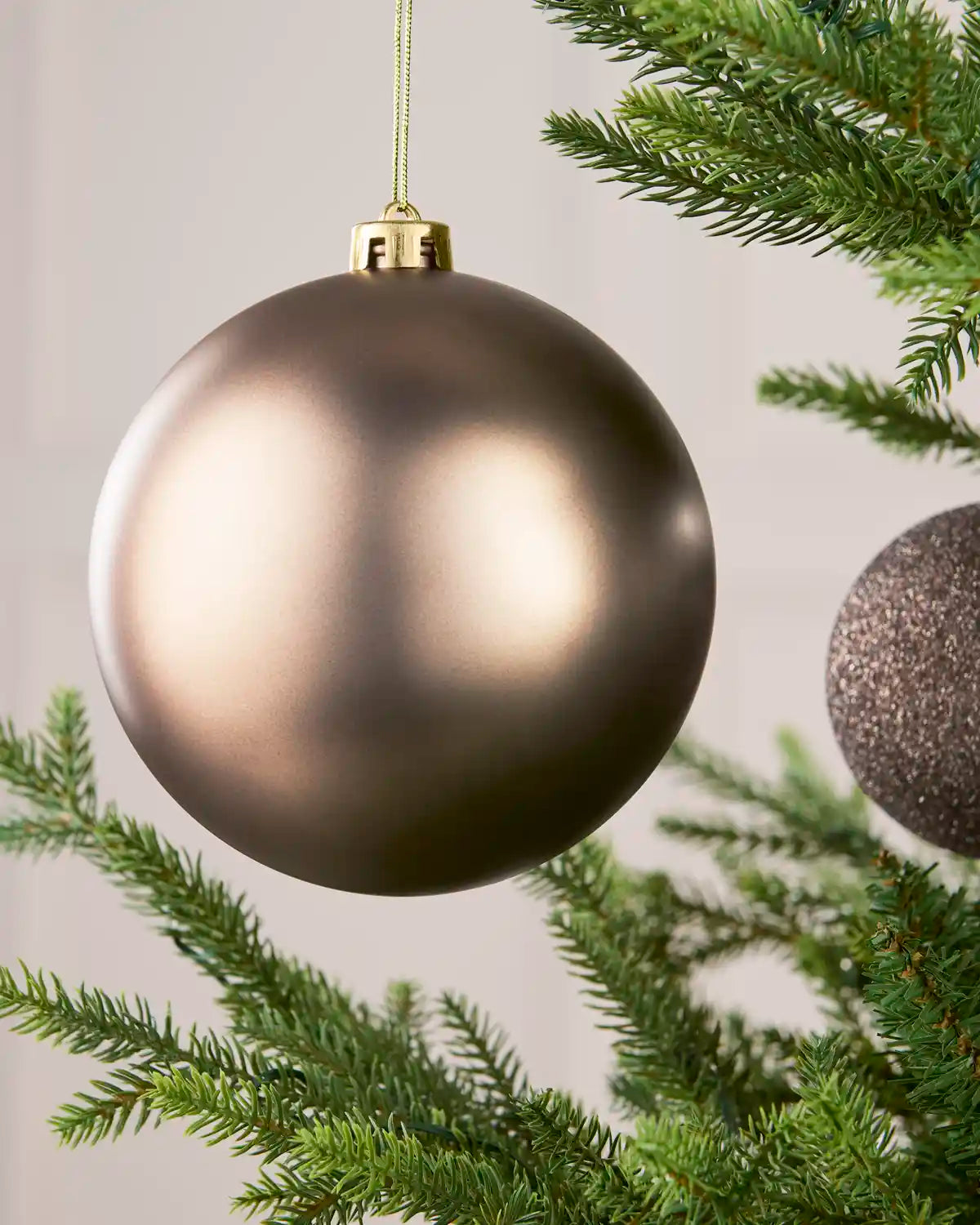 Close-up of an Mocha 15 cm oversized shatterproof bauble with a Matt finish on a Christmas tree.
