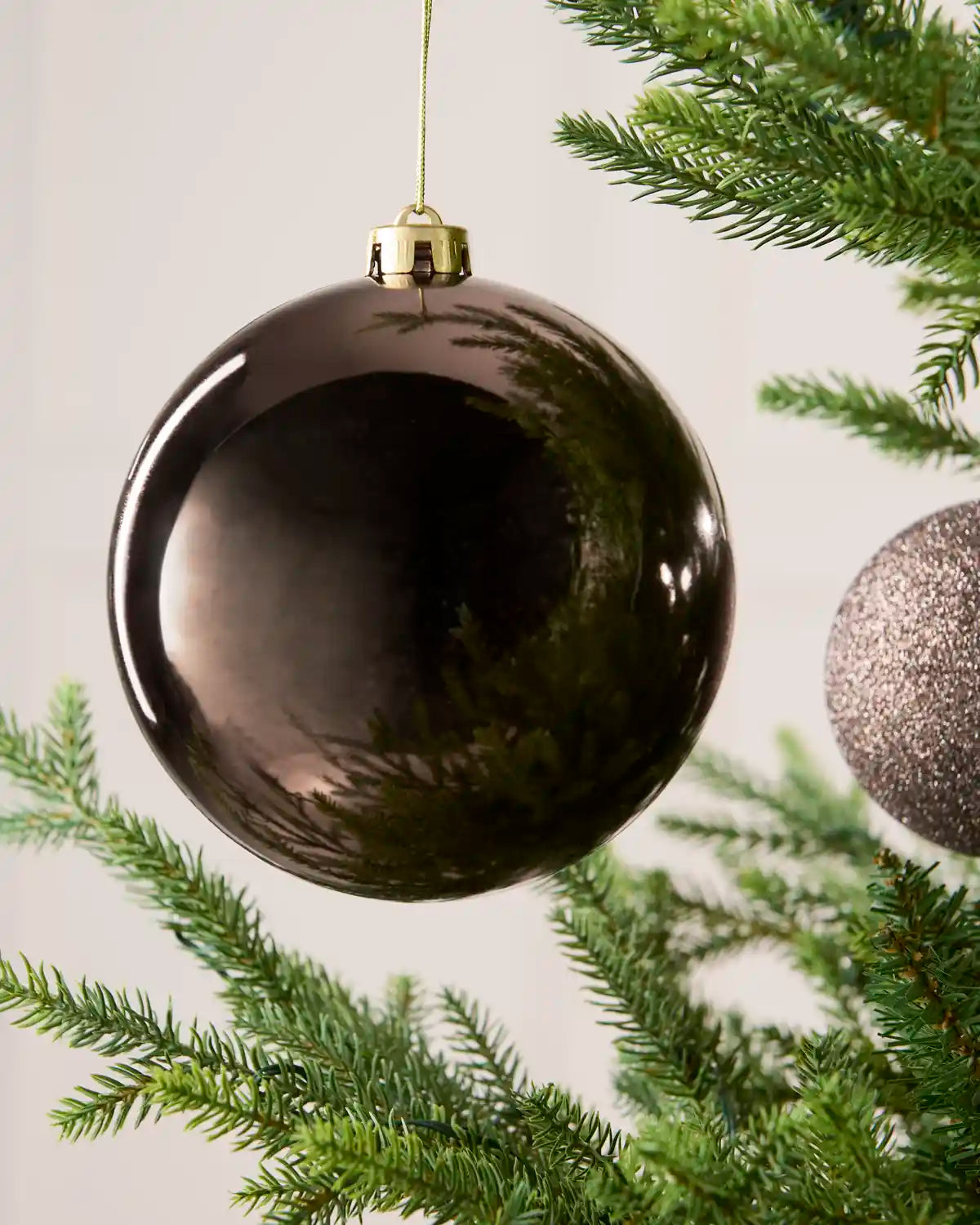 Close-up of an Mocha 15 cm oversized shatterproof bauble with a Shiny finish on a Christmas tree.
