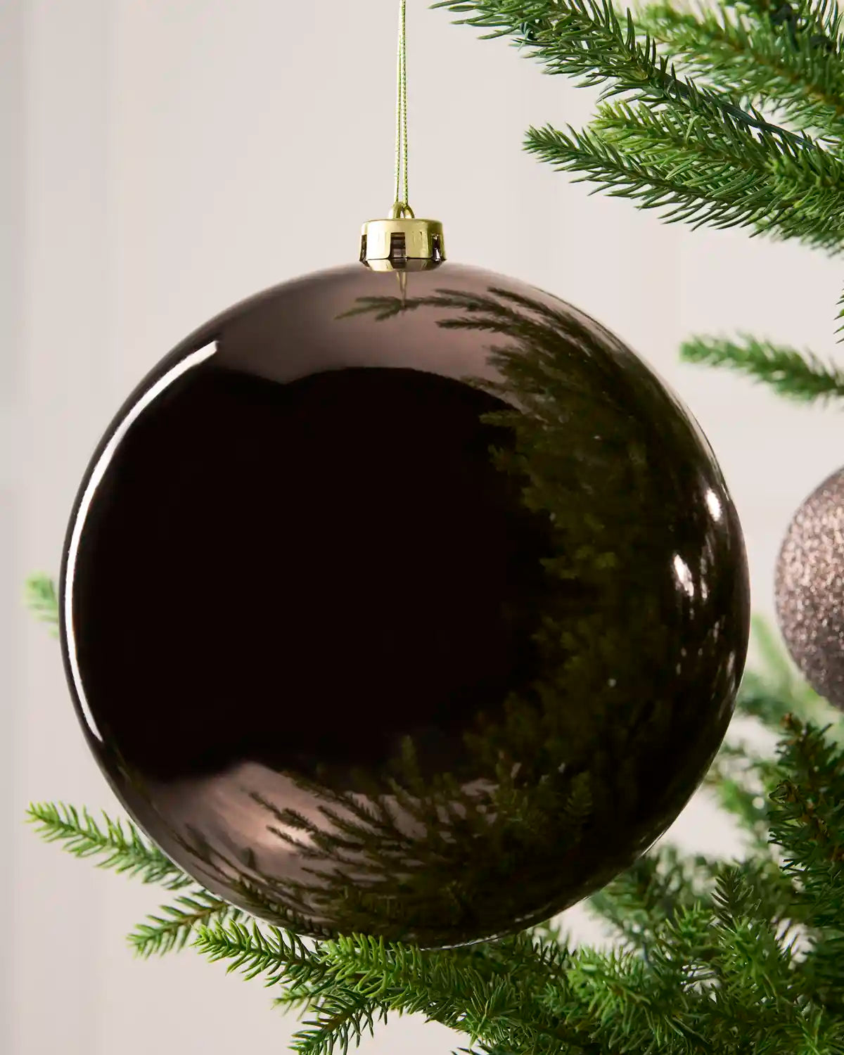 Close-up of an Mocha 20 cm oversized shatterproof bauble with a Shiny finish on a Christmas tree.
