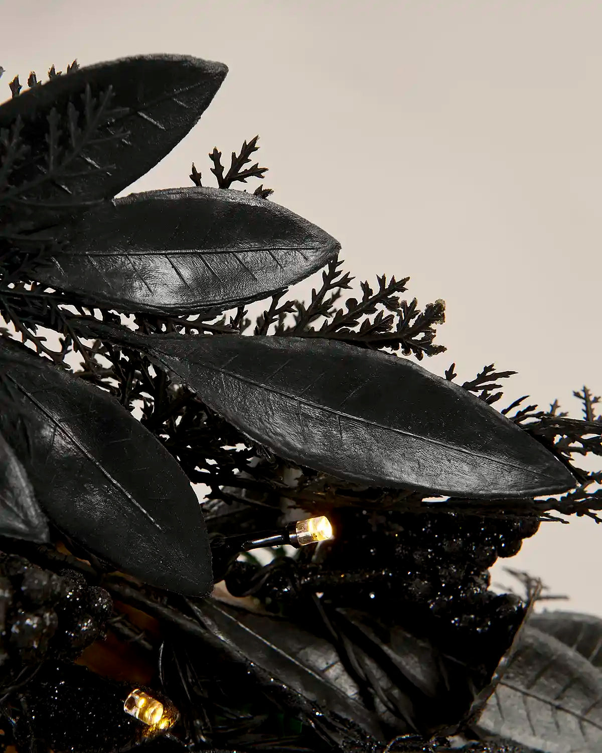 Close-up of black garland with warm white lights against a Cream background